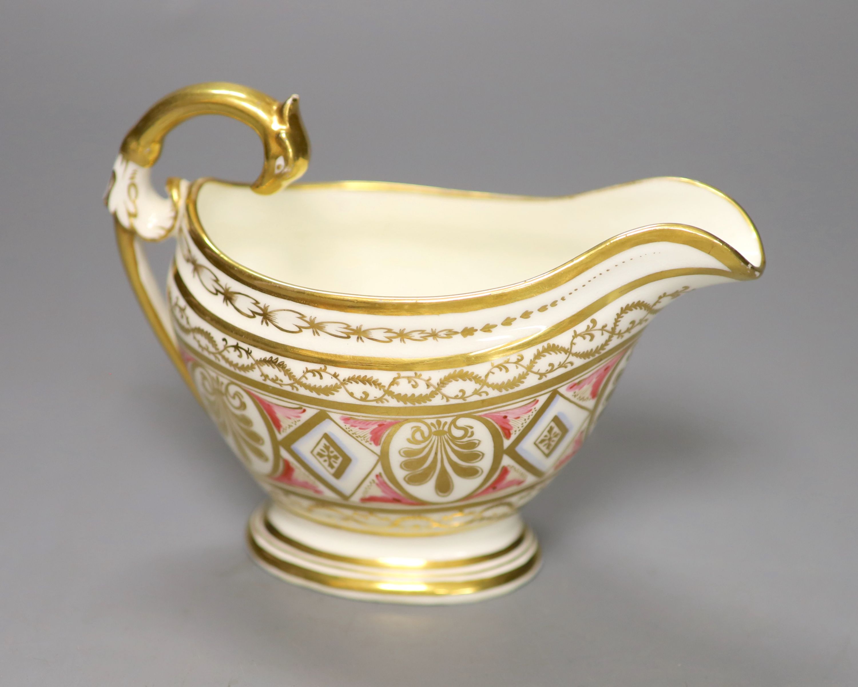 A rare English porcelain sauceboat, with swan neck handle gilded with alternating oval and diamond shaped panels and puce festoons,